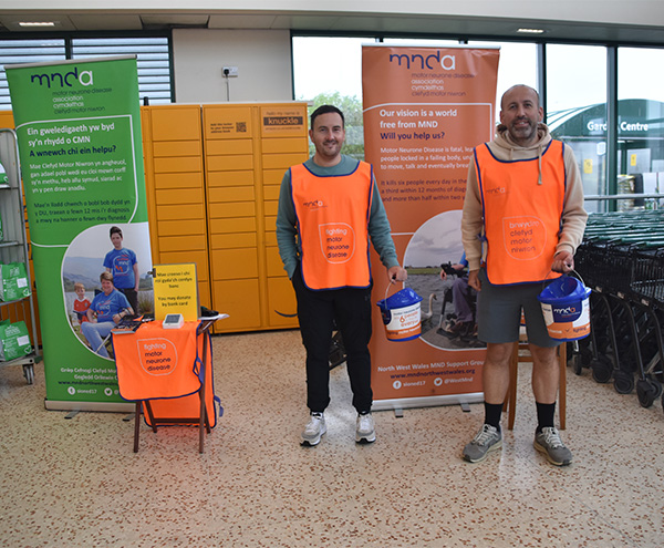 Dau person yn gafael bwced casgliad arian Yn Morrisons, Caergybi